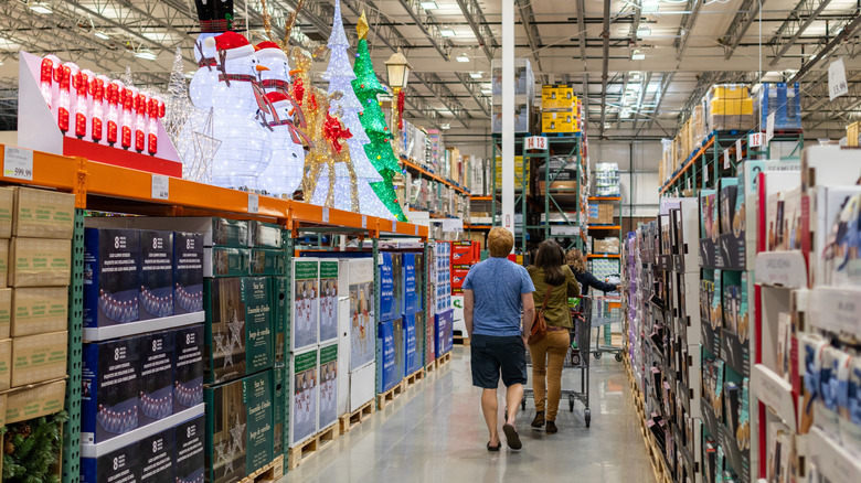 Shoppers wheel a cart down a Costco aisle with Christmas items