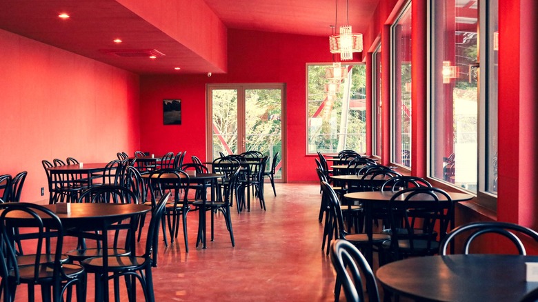 Interior of restaurant with red walls and black tables and chairs