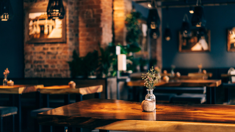 Interior of a dimly-lit restaurant favoring a table with flower display