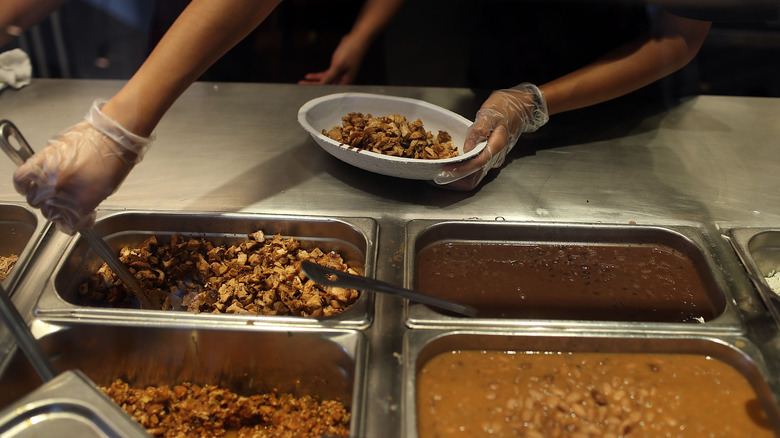 Chipotle employee scooping chicken into bowl