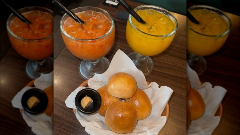 Fruity cocktails in large goblet glasses and rolls from Texas Roadhouse