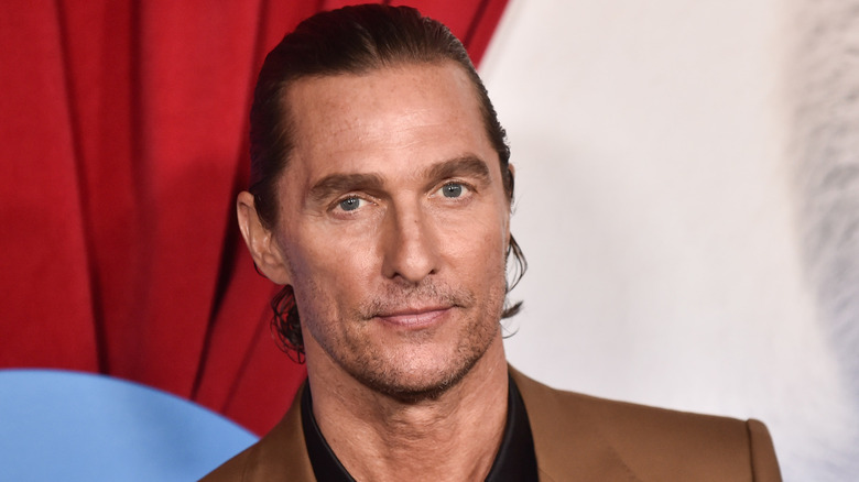 Matthew McConaughey poses in a brown suit at an event
