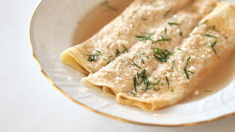 A stack of crepes on a wooden plate with seasonings
