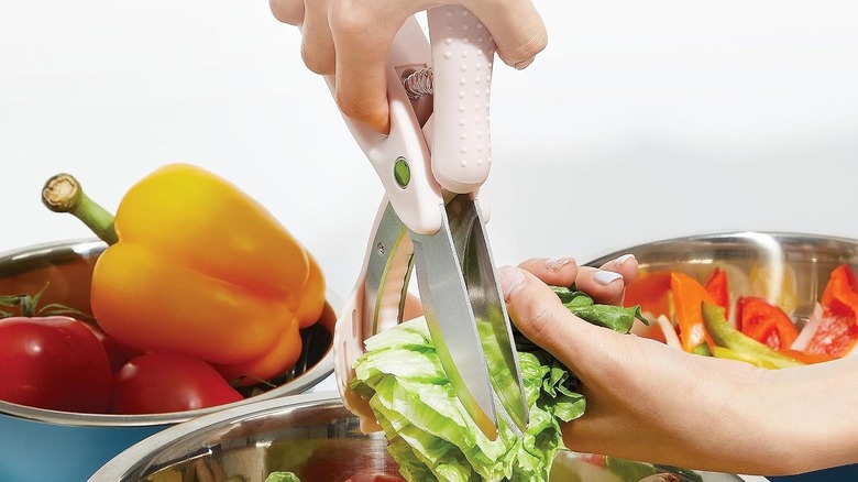 Person chopping a handful of lettuce with salad scissors