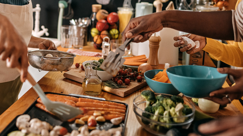 Women transfer a variety of roasted vegetables to serving bowls