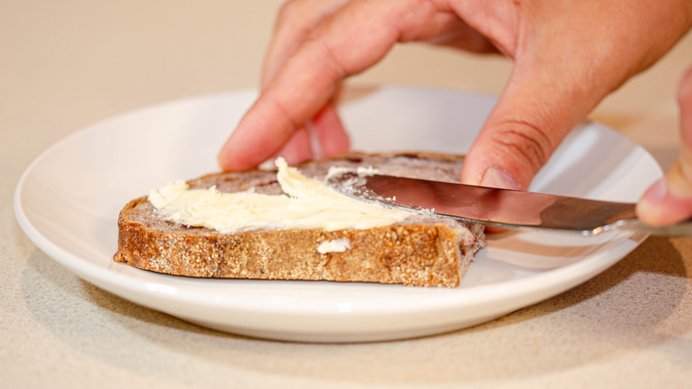 closeup hands butter bread with knife