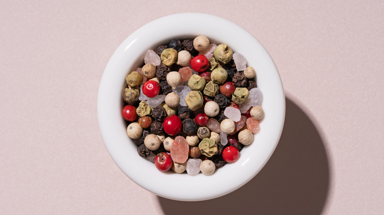 Small white bowl with assorted whole peppercorns