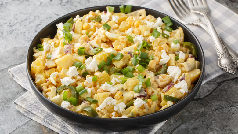 Mexican corn potato salad with crumbled cheese, jalapeños, scallions, and red onions