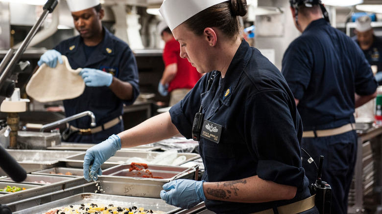 Navy cooks preparing food in ship galley