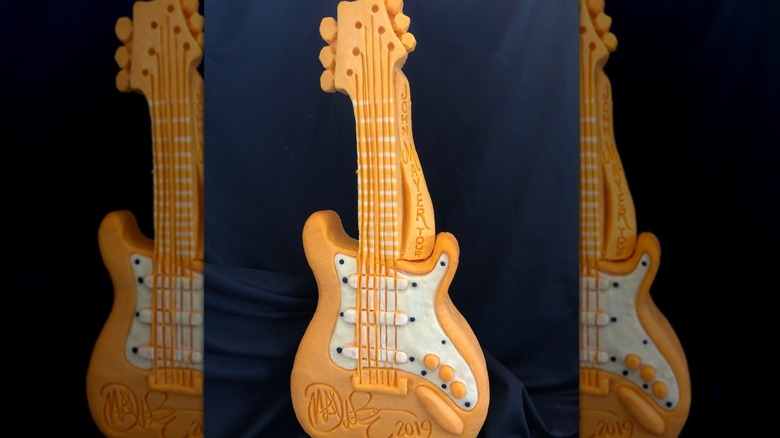 cheese sculpture of a guitar for John Mayer's 2019 tour against a black backdrop