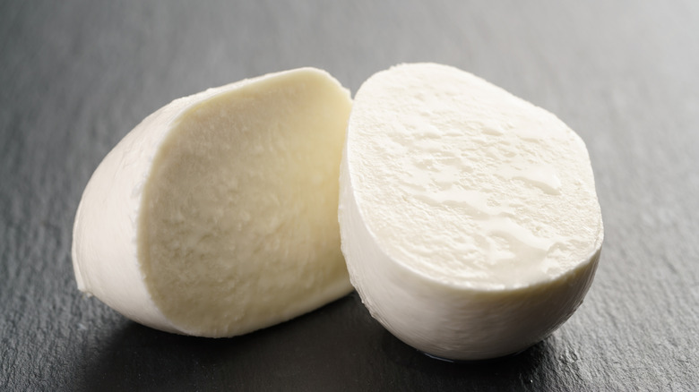 Mozzarella ball sliced in half on charcoal surface