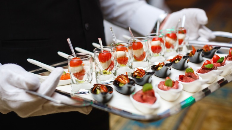 A server holding a tray of appetizers for a party.