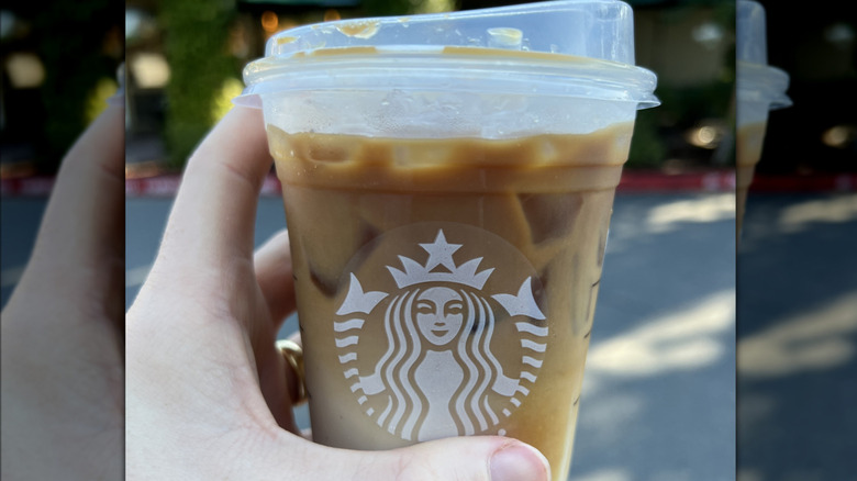 Close-up of a hand holding a Starbucks Apple Crisp Macchiato