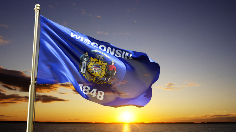 Wisconsin state flag blows with sunset in background