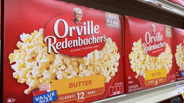 Boxes of microwave Orville Redenbacher popcorn on a supermarket shelf.