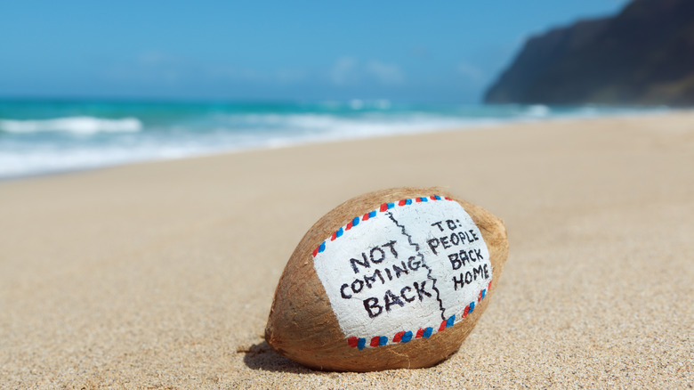 Close-up of coconut on a sandy beach with a message written on it to look like an air  mail envelope