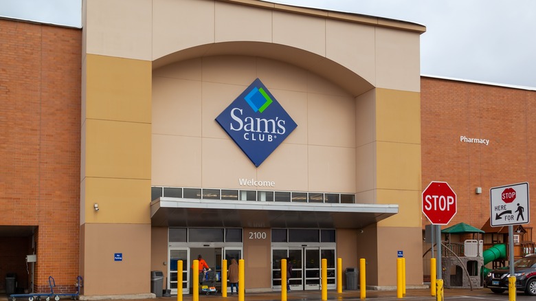 Outside of a Sam's Club, showing the blue and white logo on a cream background over the entrance doors