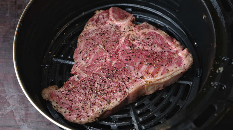 Raw beef steak in air fryer basket
