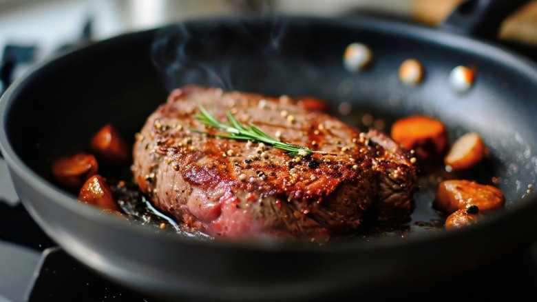 Steak in a frying pan with herbs and seasonings
