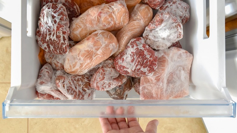 Frozen meat wrapped in plastic in refrigerator freezer compartment