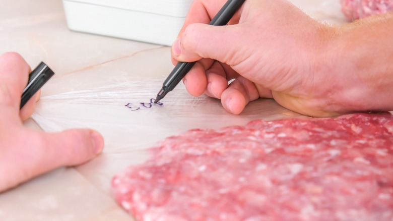 Hand labeling bag of ground meat with a black marker