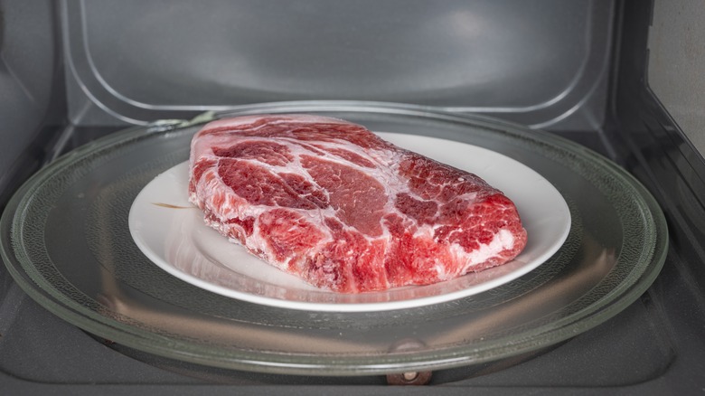 frozen meat on plate in microwave