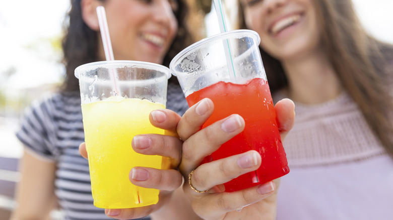 Two women holding slushies in plastic cups
