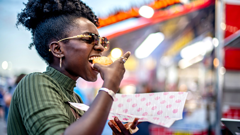 a woman enjoys a bite of state fair food