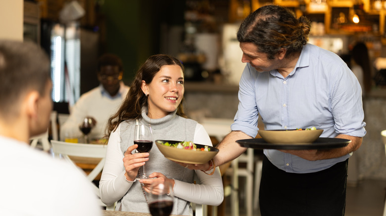 girl being served salad by waiter