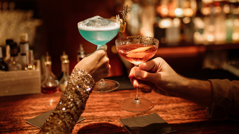 Two guests toast craft cocktails at a bar