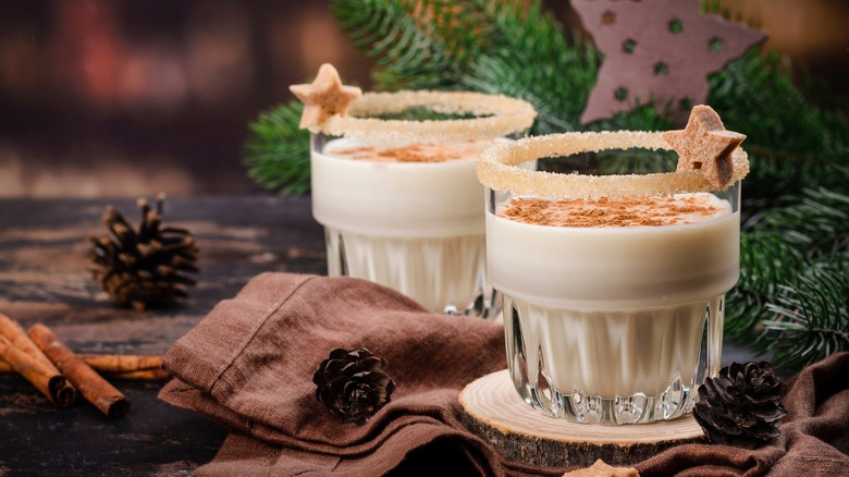 Homemade eggnog with cinnamon in glass on wooden table