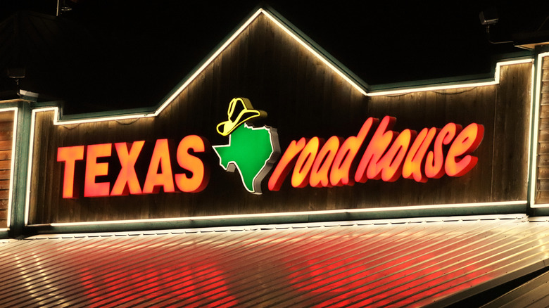 A Texas Roadhouse sign lit up at night.