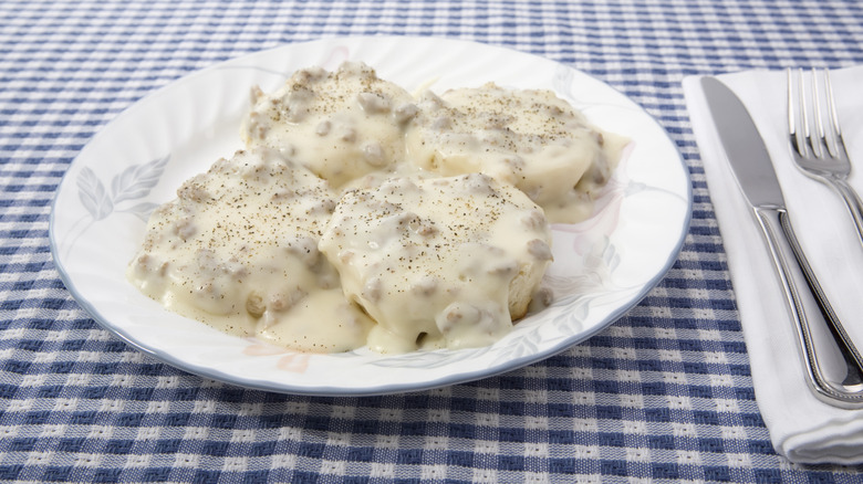 Biscuits and gravy on a white plate with cutlery