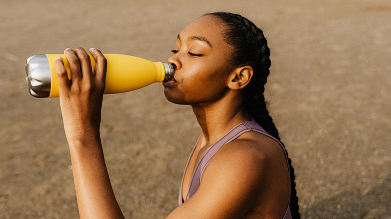 Woman drinking from metal water bottle