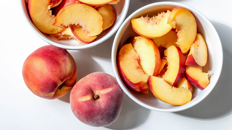 whole and cut yellow peaches in a bowl