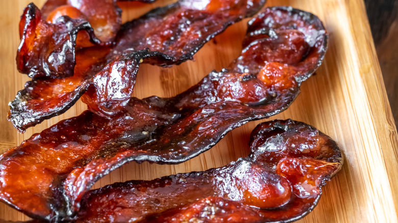 Strips of candied bacon on a wooden board