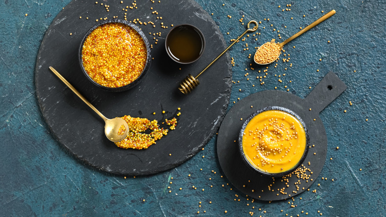 Bowl of Dijon mustard and sweet honey on dark background