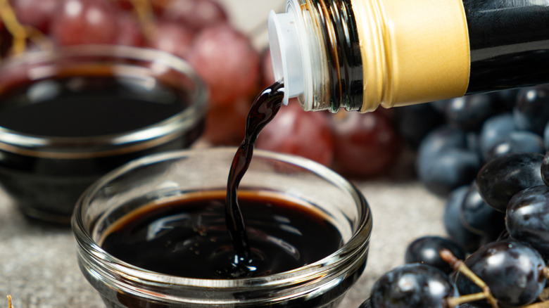 Balsamic vinegar being poured from a bottle into a small glass bowl