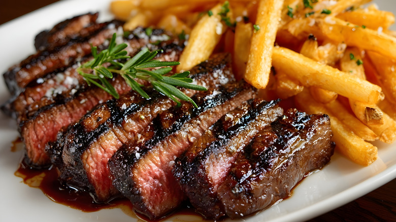 Juicy slices of steak on a white plate with a glaze dripping off of them.