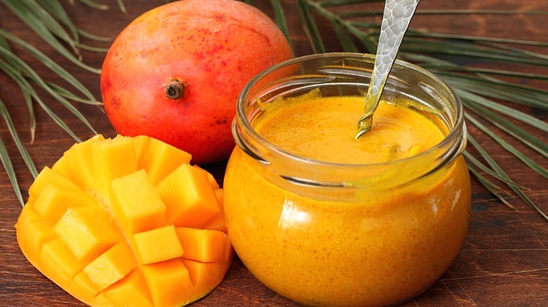 A jar of amba sauce with fresh mango