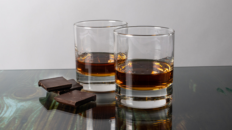 Two rocks glasses of bourbon and two squares of chocolate