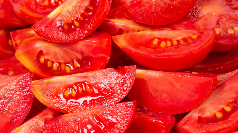 Close-up of fresh Roma tomatoes sliced into quarters, showing their thick flesh, low seed count, and vibrant red color.