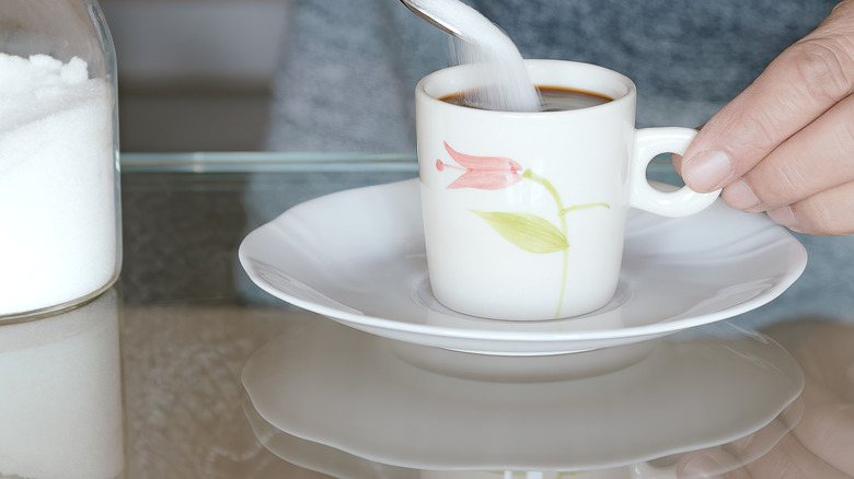 Person adding sugar to coffee