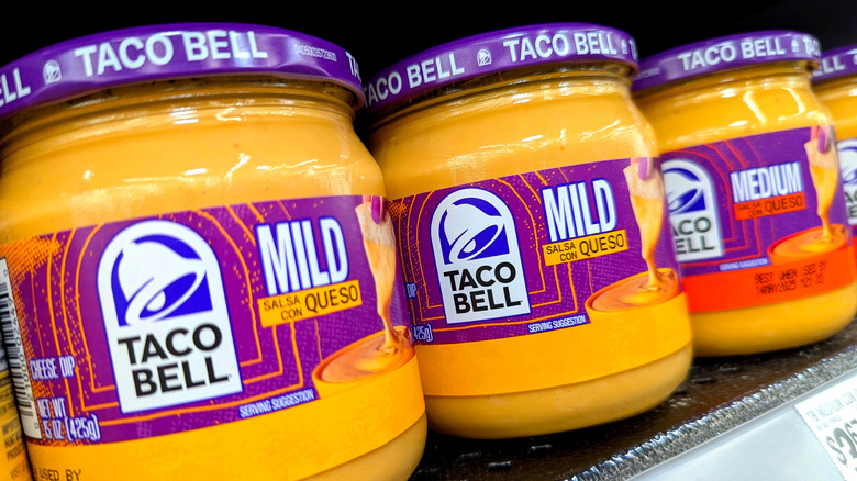 Jars of Taco Bell nacho cheese on a grocery store shelf