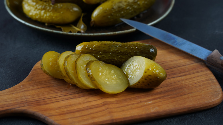 Sliced pickles on a wooden board with a knife