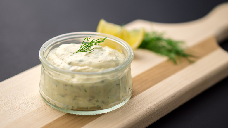 A small ramekin of tartar sauce topped with dill