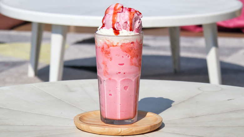A strawberry milkshake on a table outside.