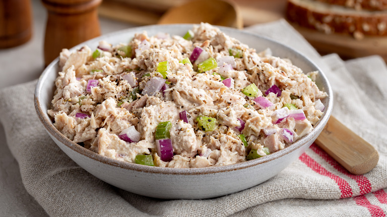 Tuna salad made with chopped red onion and celery in a pale-colored bowl