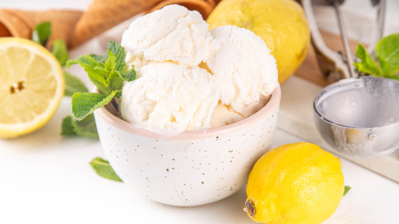bowl of lemon sorbet with mint leaves in a bowl surrounded by whole lemons