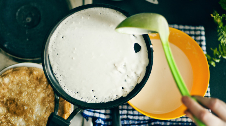 Crepe batter being cooked in a black pan